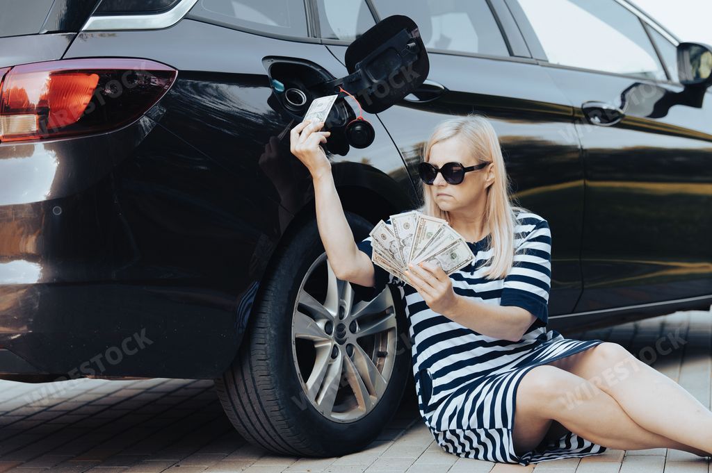 A blonde woman counting her money and filling her car with petrol