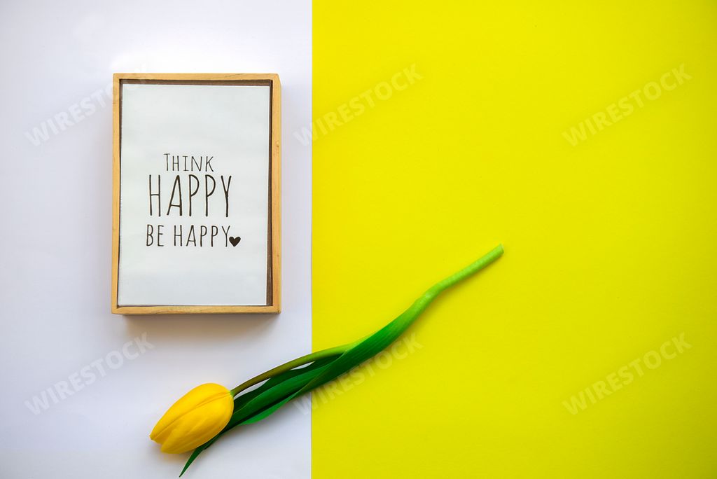 Motivational words of wish in a frame,think happy be happy on white yellow spring color tulips flower background