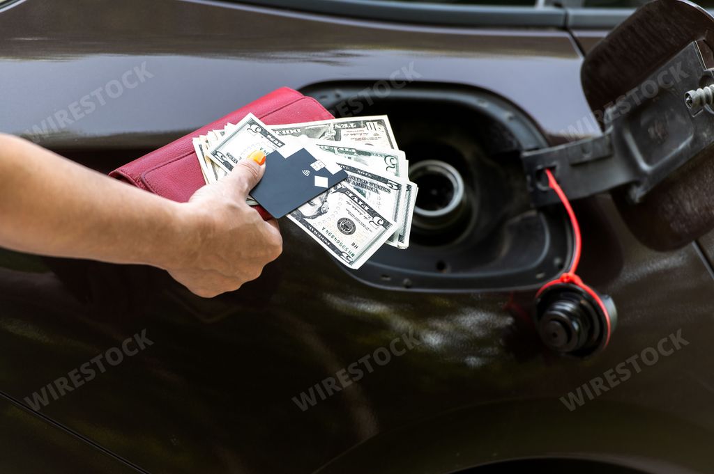 A blonde woman counting her money and filling her car with petrol