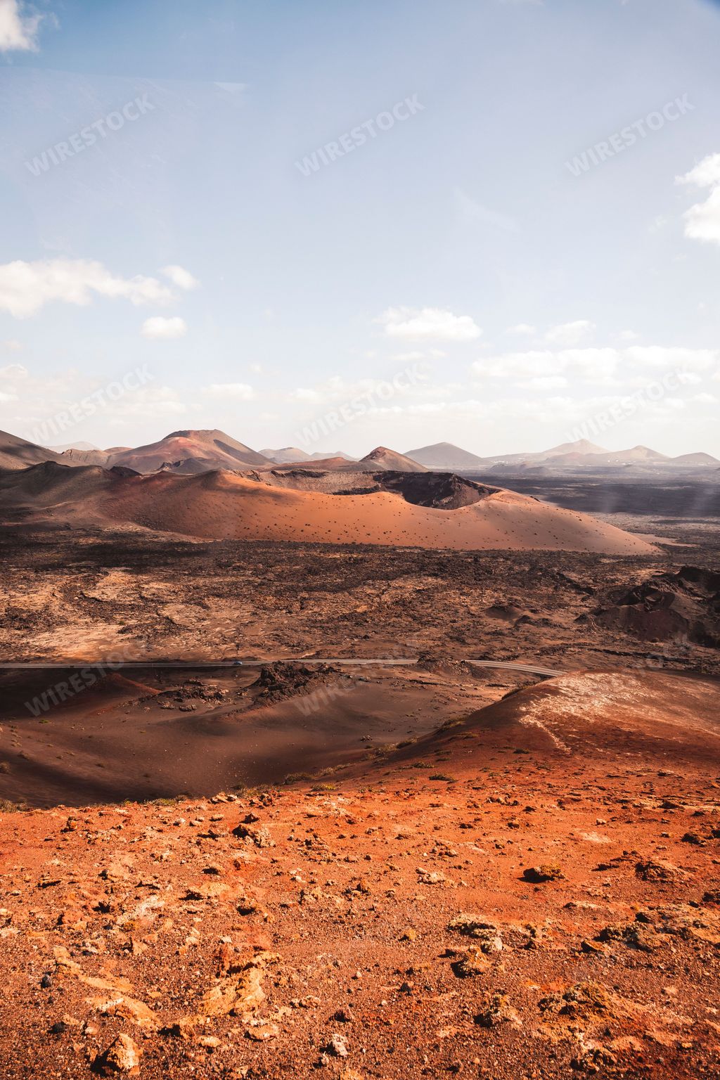 A vertical shot of a desert on a sunny day with a cloudy blue sky in the background