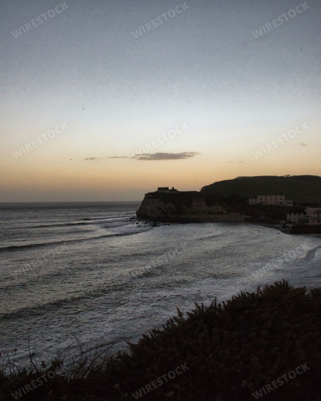 A cliff on the isle of Wight pictured with the calm surf in the foreground.