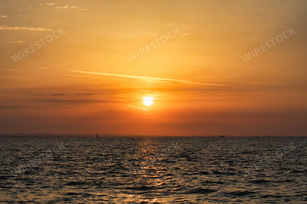 A scenic shot of a golden sunset and its reflection on the surface of a calm sea