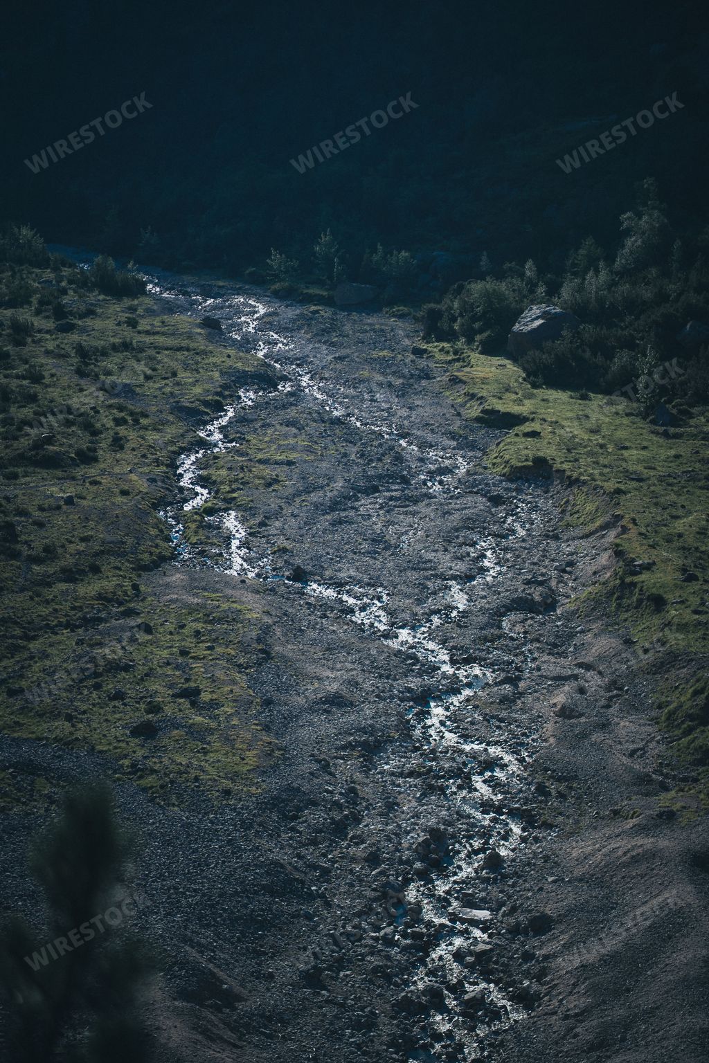 A vertical high angle view of a half dry river flowing under the Zugspitze peak in Germany