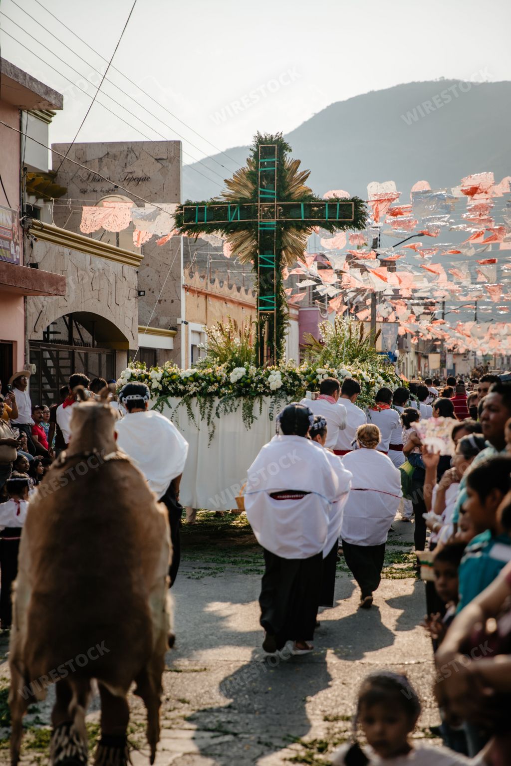 People in religious robes carrying a giant cross during The annual dancing parade for the city