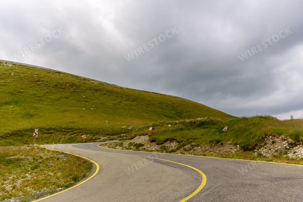 A scenic view of the Transalpina road surrounded by greenery on a cloudy day, Romania