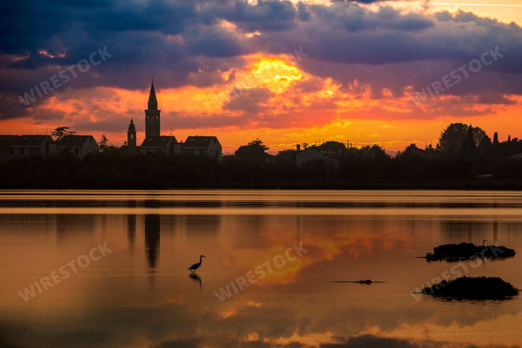 A scenic sunset over a lake with old medieval buildings on its coast, cool for background