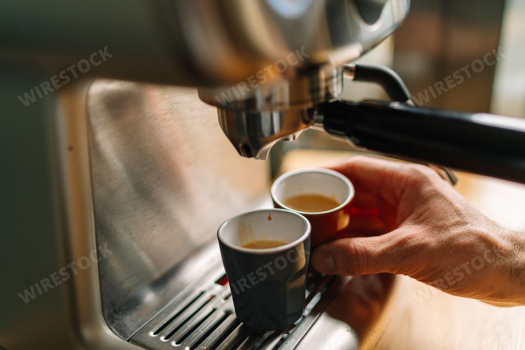 Close-up of a barista making espresso with a coffee machine in a cozy cafe setting.