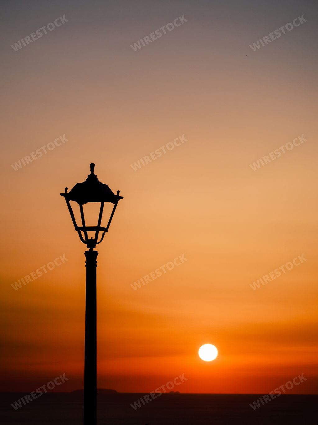 A silhouette of street lamp with background of sunset