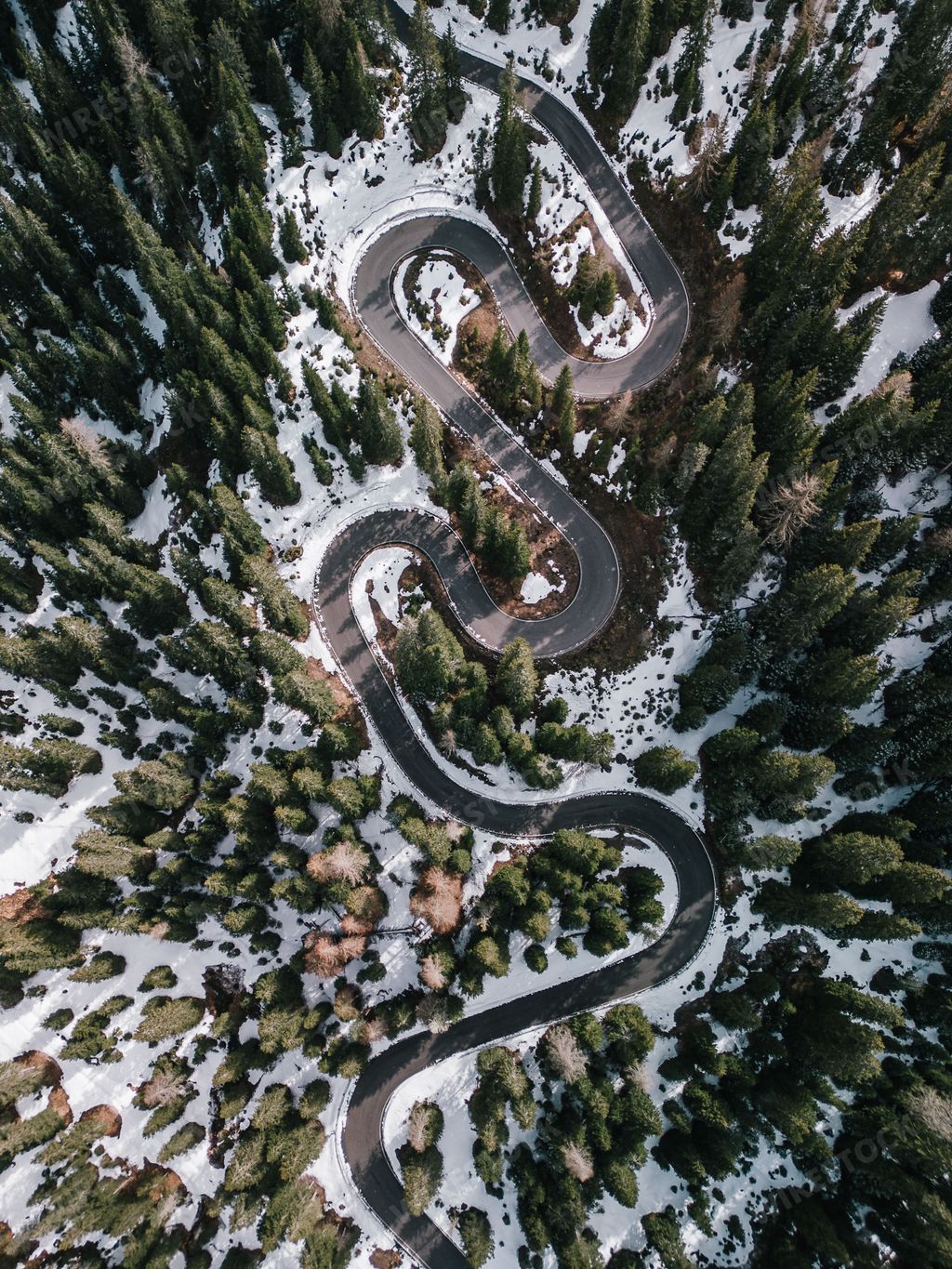 An aerial view of the winding Snake Road in winter in the Dolomite Alps of Italy.