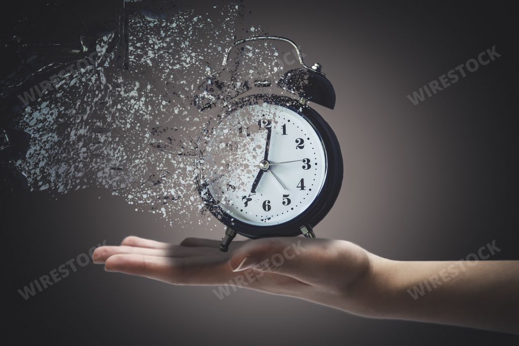 Hand holding analog clock with scatter effect. Concept of death and lack of time