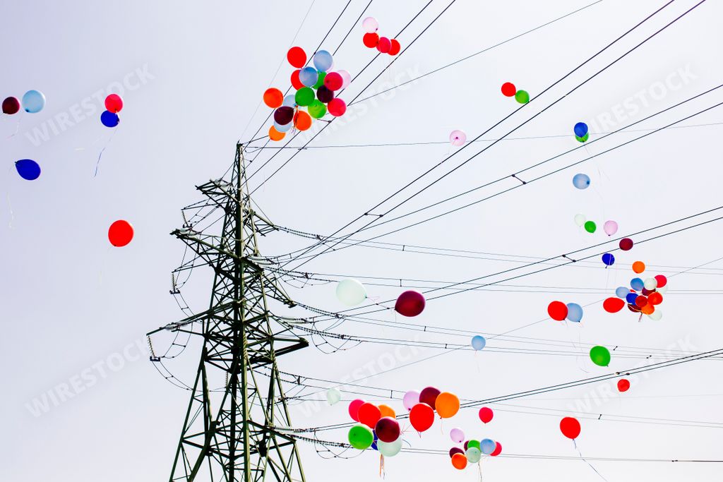 Colorful balloons flying through electrical power lines