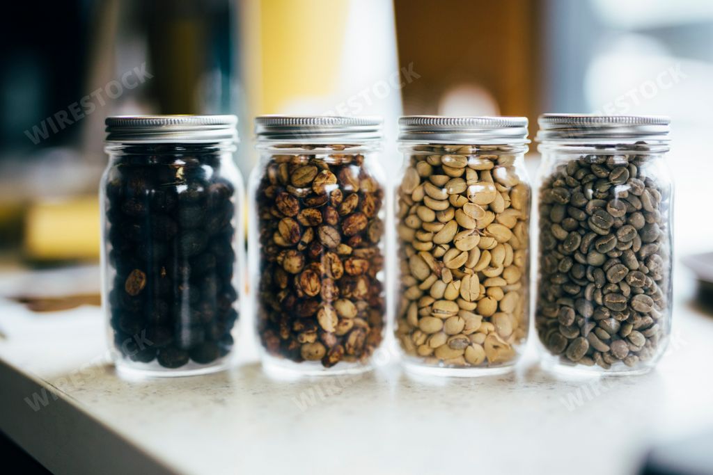 a different coffee beans in glass jars on a white surface.