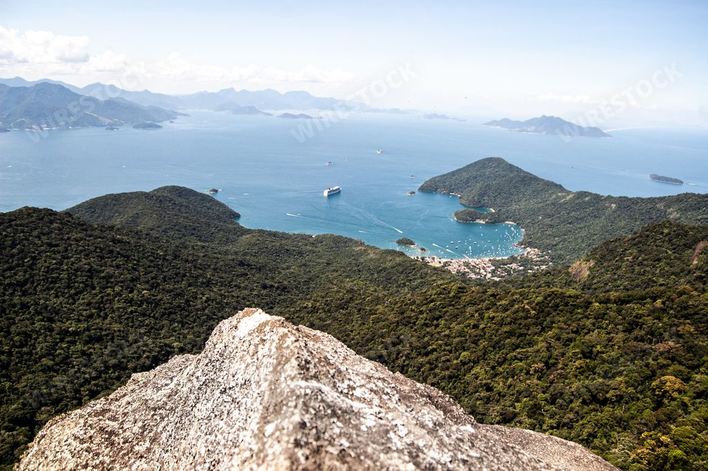 A beautiful shot of a seashore with forested mountains in Pico de Papagayo, Ilha Grande, Brazil