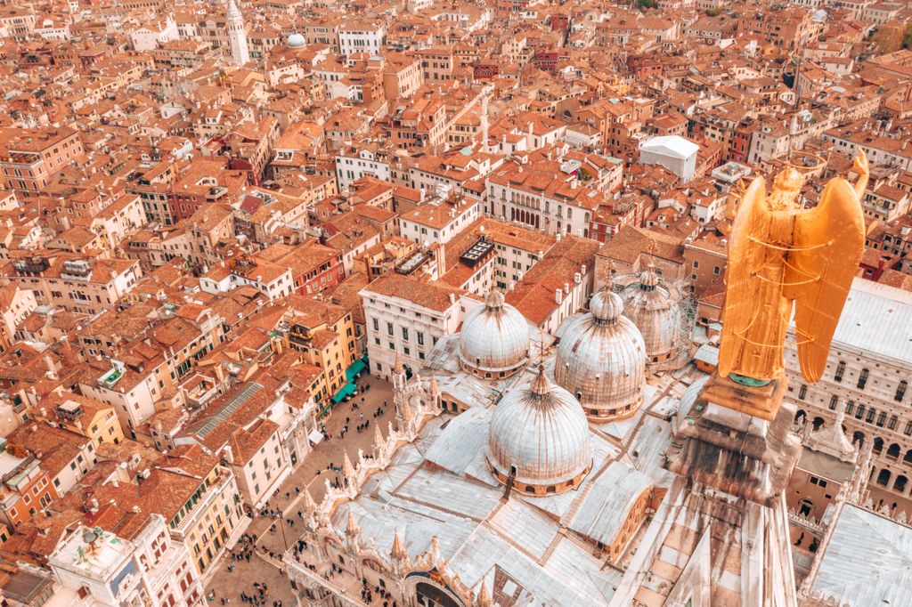 An aerial view of Piazza San Marco with the golden angel statue above the city in Venice, Italy