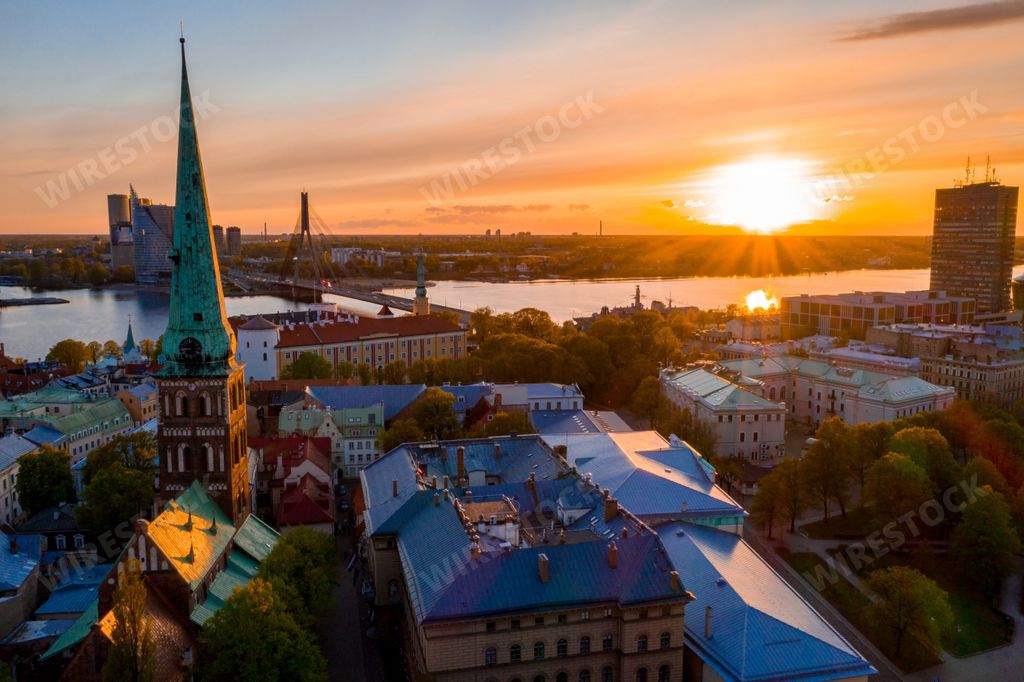 An aerial view of a cityscape with trees and tall buildings at sunset