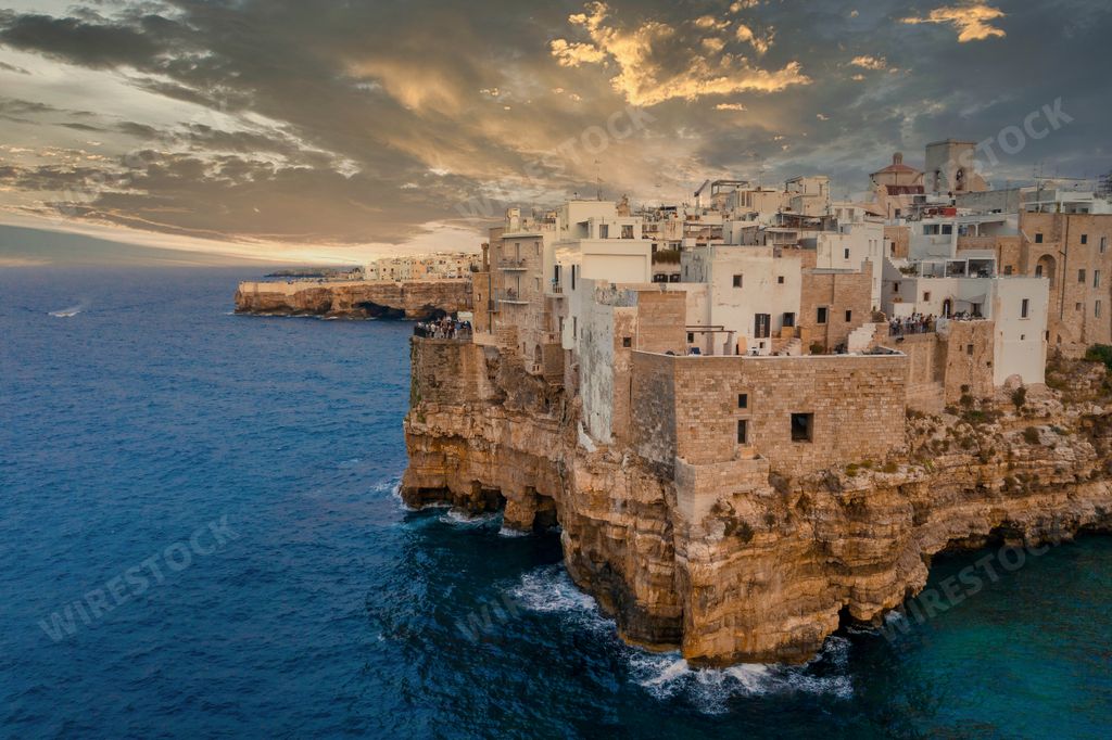 An aerial shot of ancient city with old houses on the top of the rocky cliff surrounded by the sea