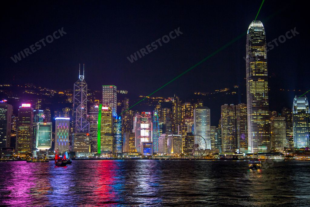 A view of a skyline at night with skyscrapers and laser beams on a dark sky background