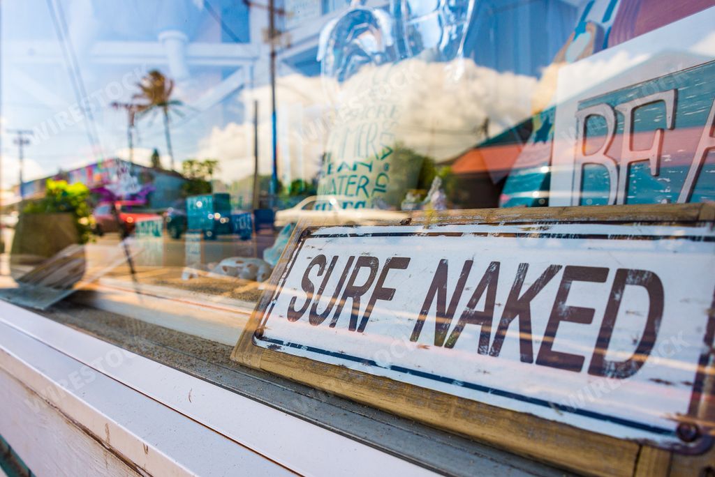 A closeup of "Surf Naked"  written on a sign behind the glass on the island of Maui, Hawaii