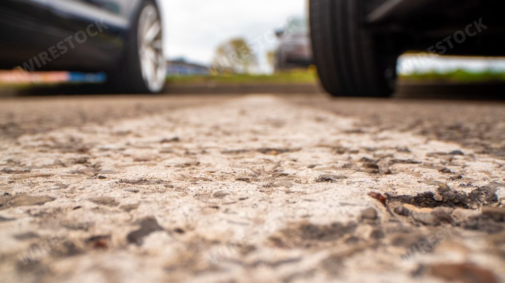 A closeup shot of parking asphalt on a background of car wheels