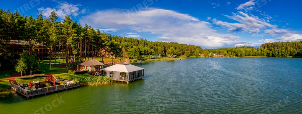 A panoramic shot of houses on a lake surrounded by greens near the Walchwil village in Switzerland