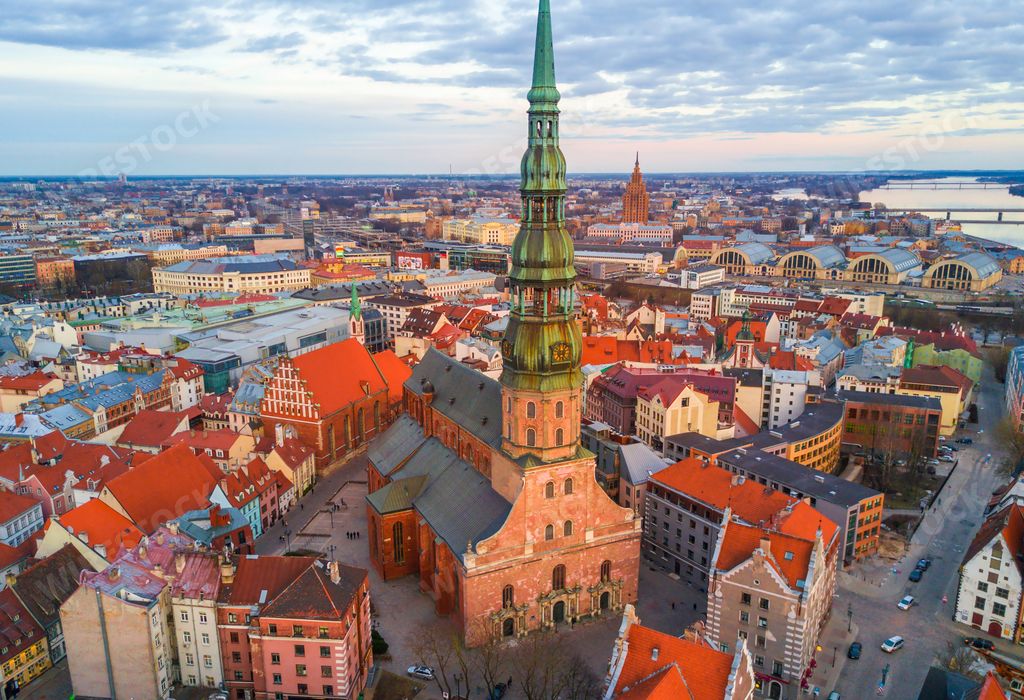 The St. Peter's Church surrounded by buildings under a cloudy sky in Riga, Latvia