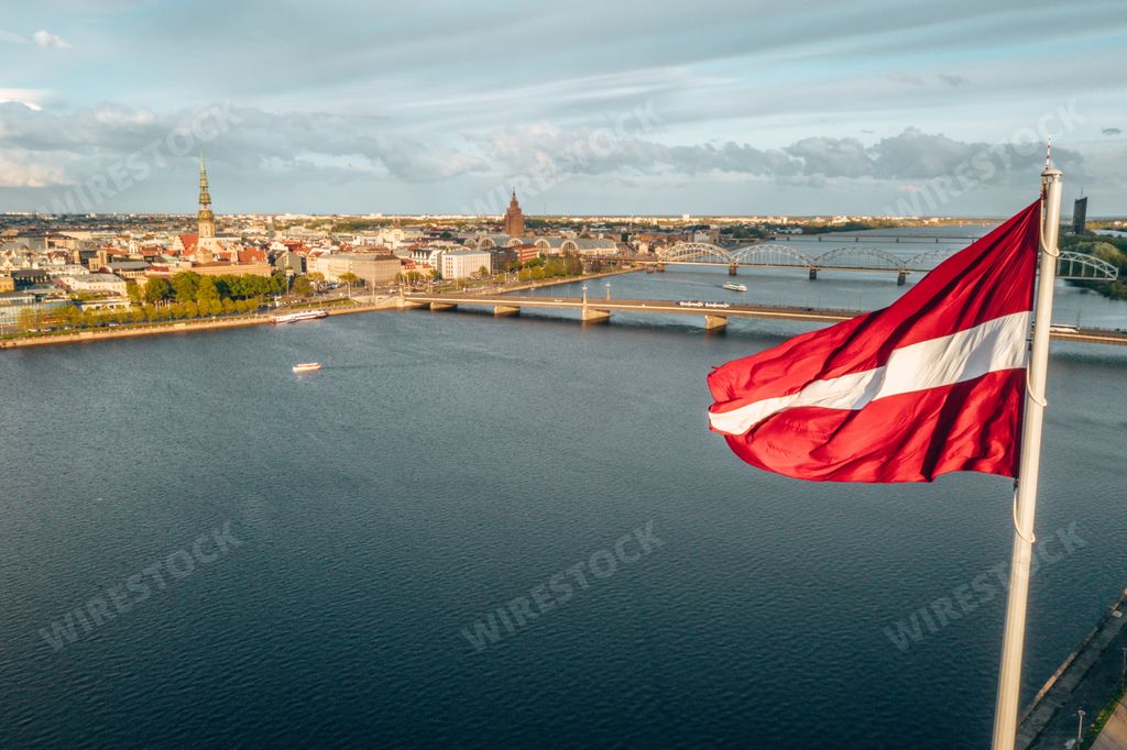 An aerial shot of Riga city with a big Latvian flag in the foreground at golden hour