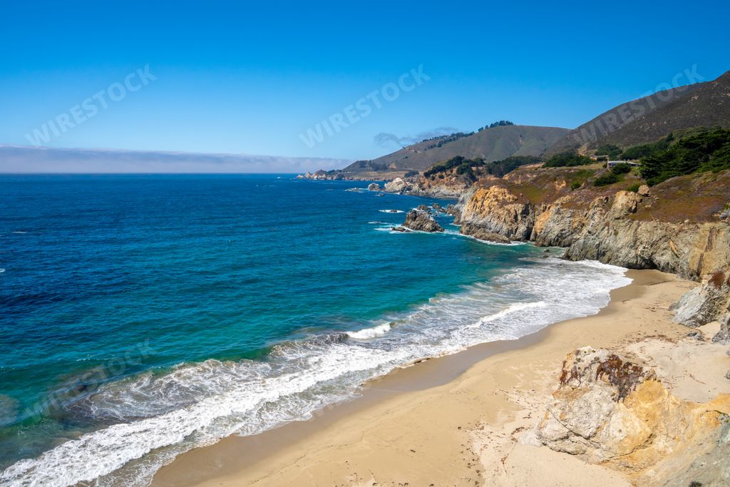 A beautiful scenery of the peaceful sea surrounded by high rocky cliffs in California, USA