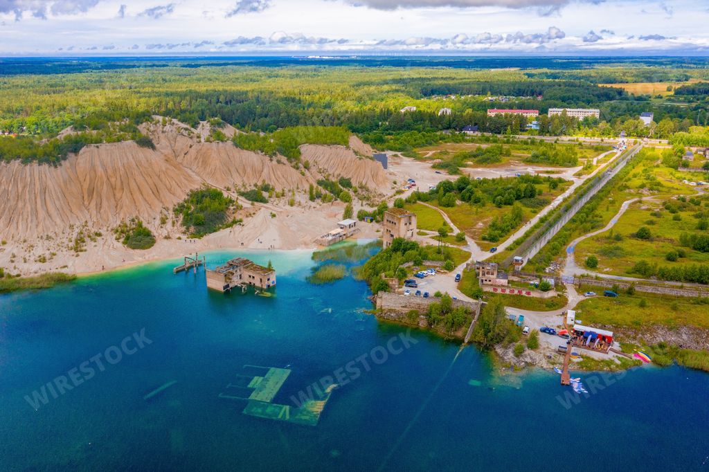 An aerial view of the Rummu abandoned prison, partially submerged in a lake surrounded by forest trees in Tallinn, Estonia