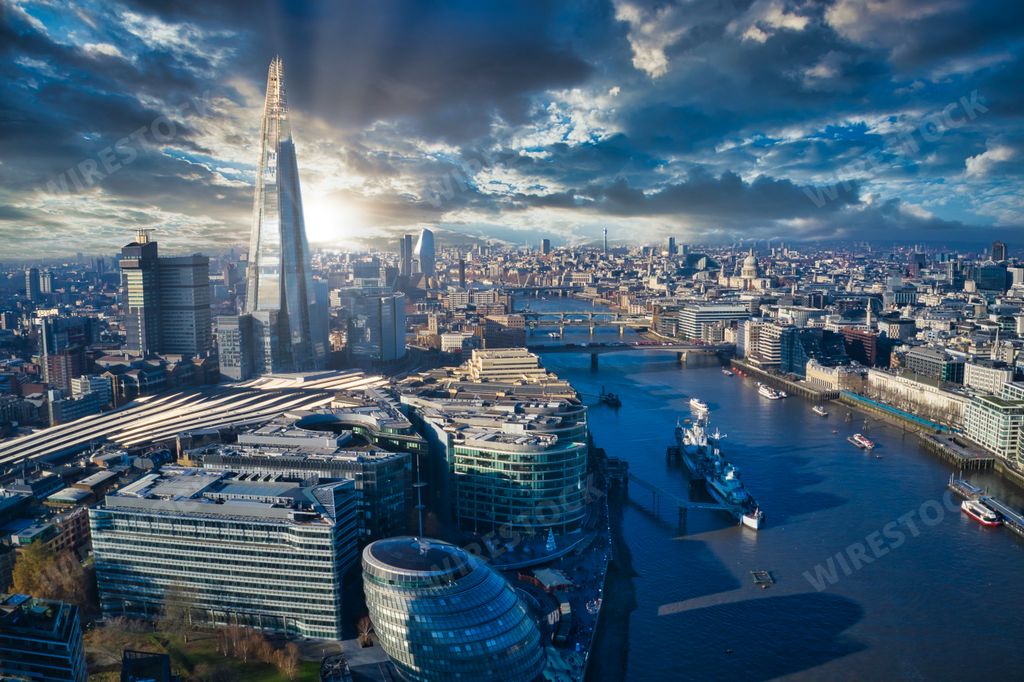 A stunning aerial view of London with Thames river, Shard and tall skyscrapers under the cloudy sky