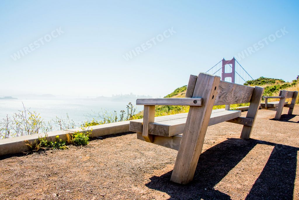 A mesmerizing view of the Golden Gate Bridge with a wooden bench on the foreground