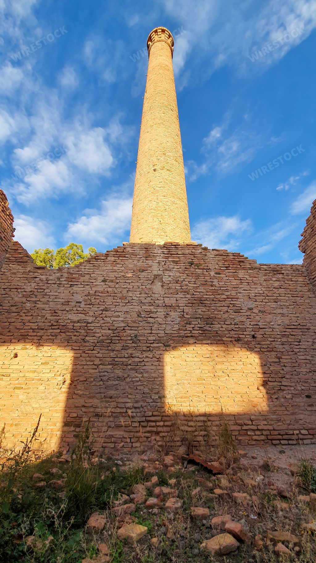 A vertical shot of an old mud brick industrial chimney