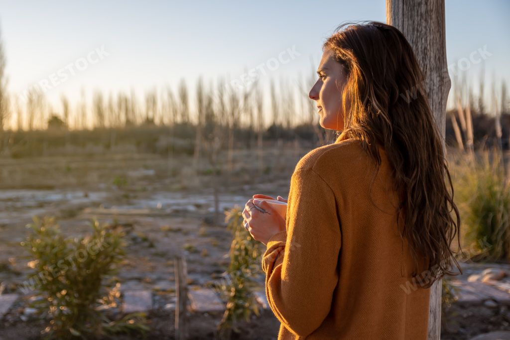 A pretty Hispanic woman drinking coffee and watching the sunset