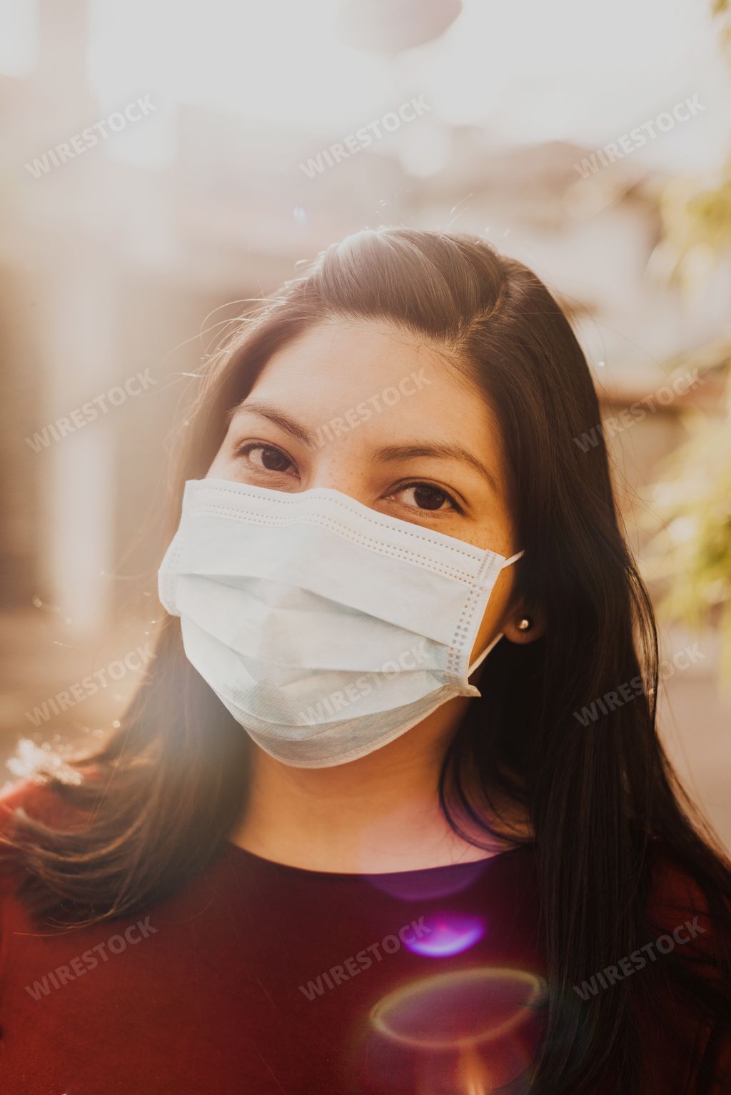 A vertical shot of a Hispanic female wearing mask and gloves on a sunny day