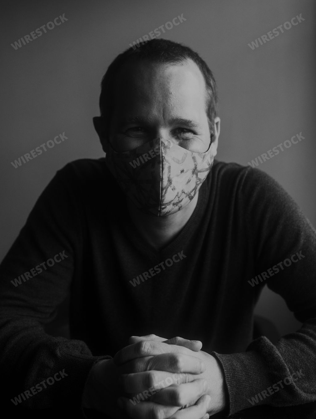 A grayscale shot of a caucasian man smiling wearing a face mask-concept of positivity