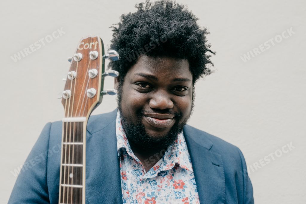 A shallow focus of a black man holding a guitar
