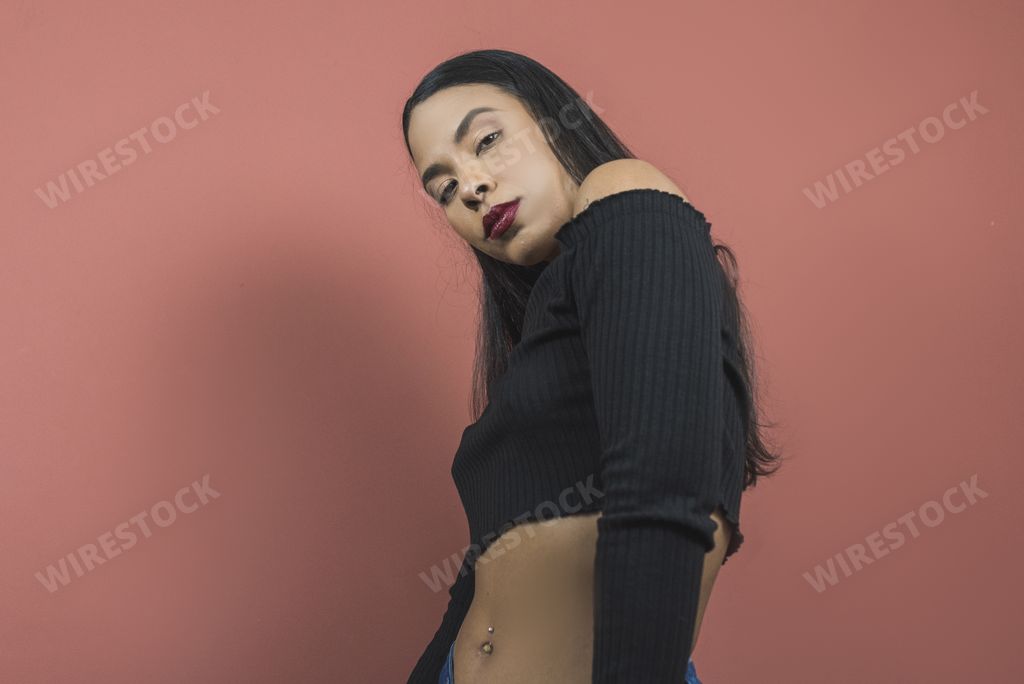 A beautiful shot of a sexy Hispanic woman posing on a pink background