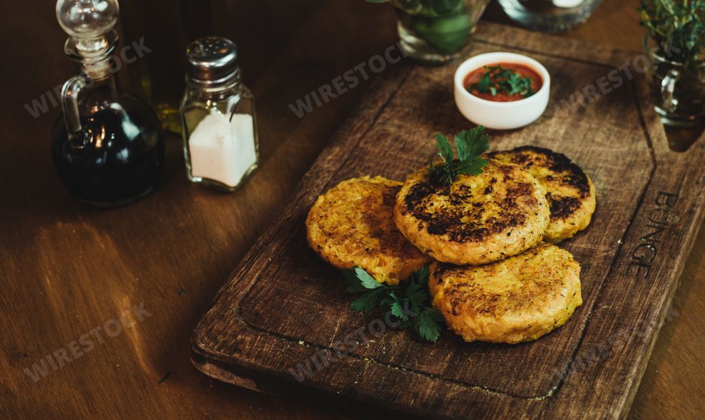 A high angle shot of vegan cutlets on a wooden tray served with sauce and seasonings