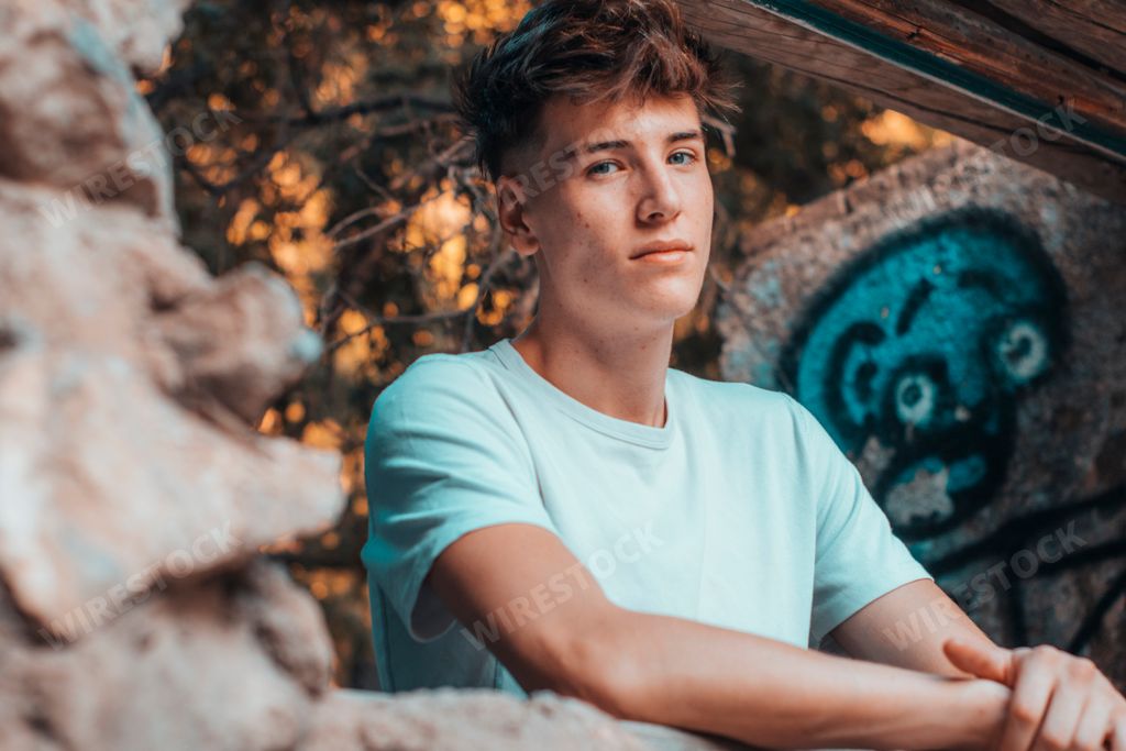 A blonde Spanish man leaning on the stone and looking at the camera