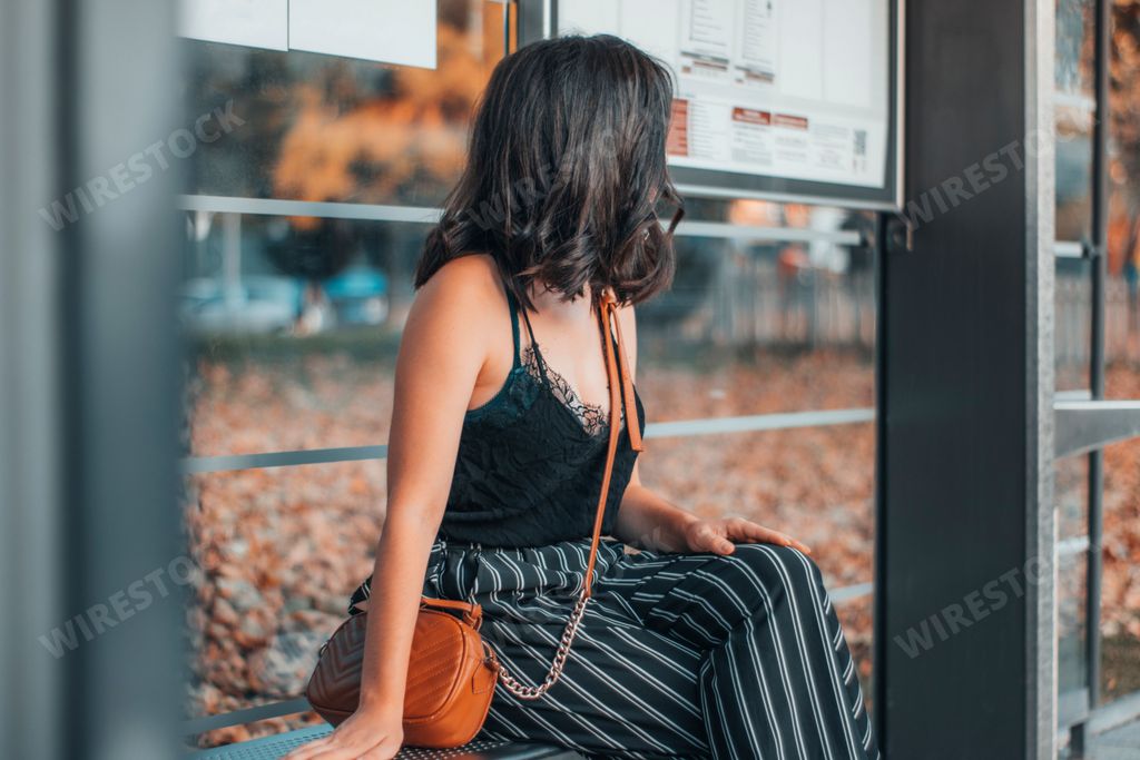 A Caucasian woman sitting at a bus station