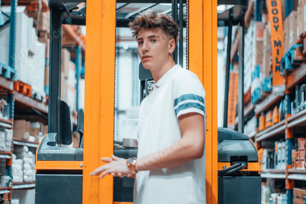 A Caucasian guy standing on a loader inside a stock store and looking to the camera