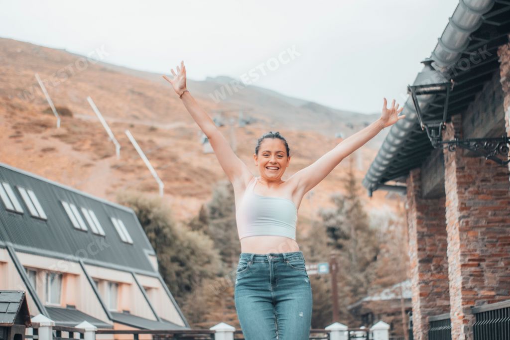 A young girl standing with her hands up on the road of a village in the mountains