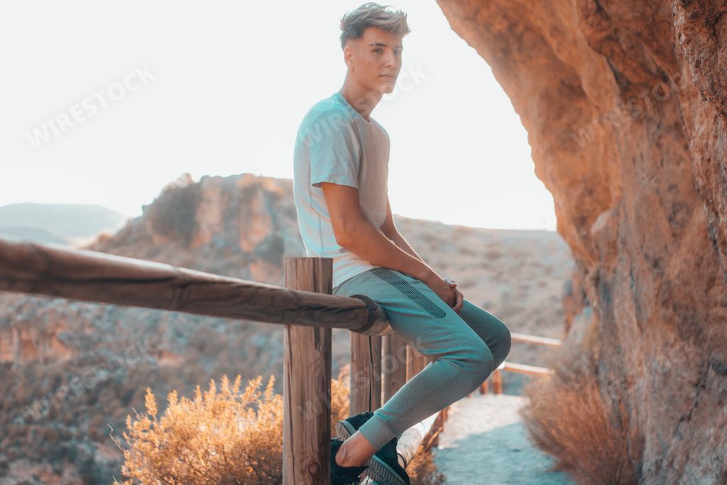 A Caucasian man leaning on the wooden railing on the mountain