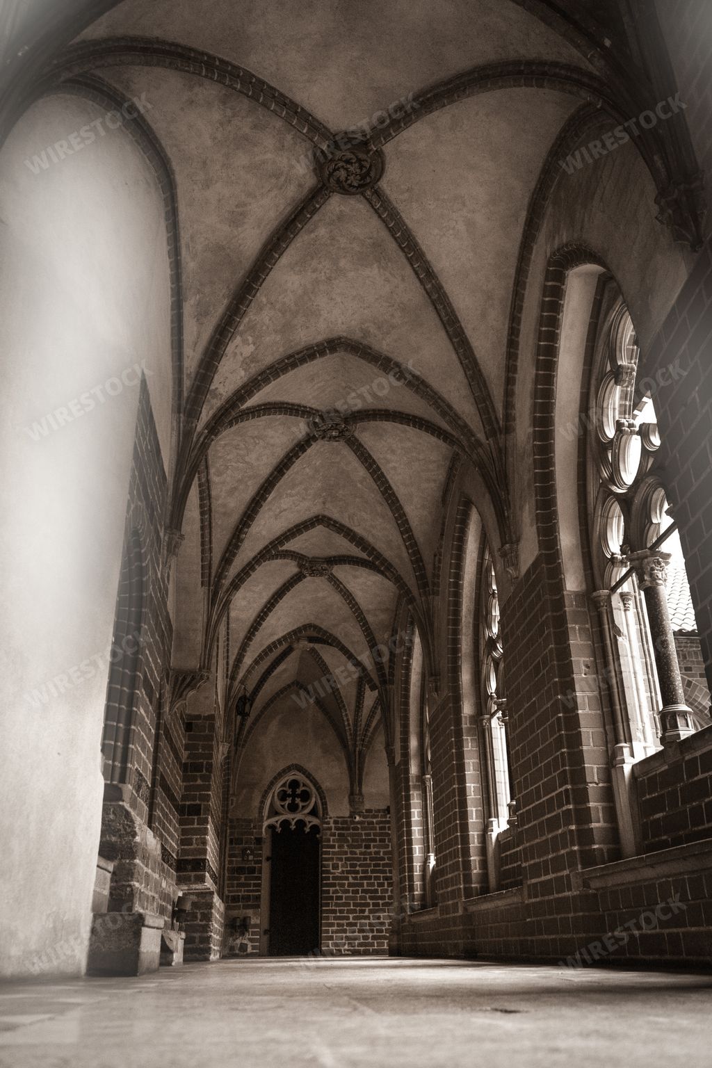 A grayscale shot of the interior of a Gothic-style castle corridor in Malbork, Poland
