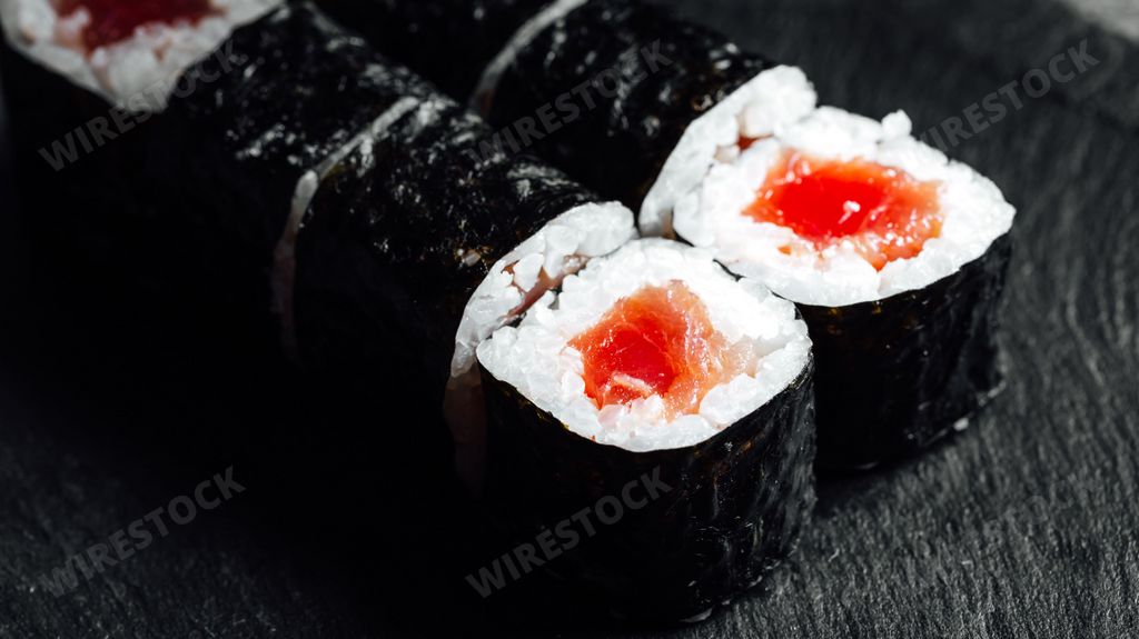 A closeup of a set of fresh delicious Tekka Maki rolls on a black plate