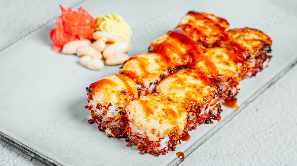 Delicious fresh hot sushi rolls covered in cheese on a white plate
