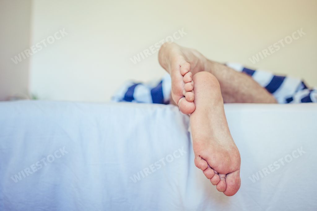 A closeup shot of a male sleeping in the bad, man feet