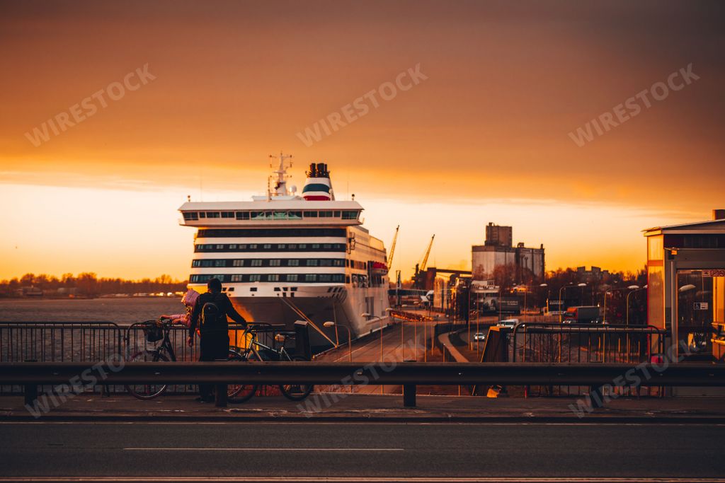 The cyclists on the road with a cruise ship in the background. Riga, Latvia.