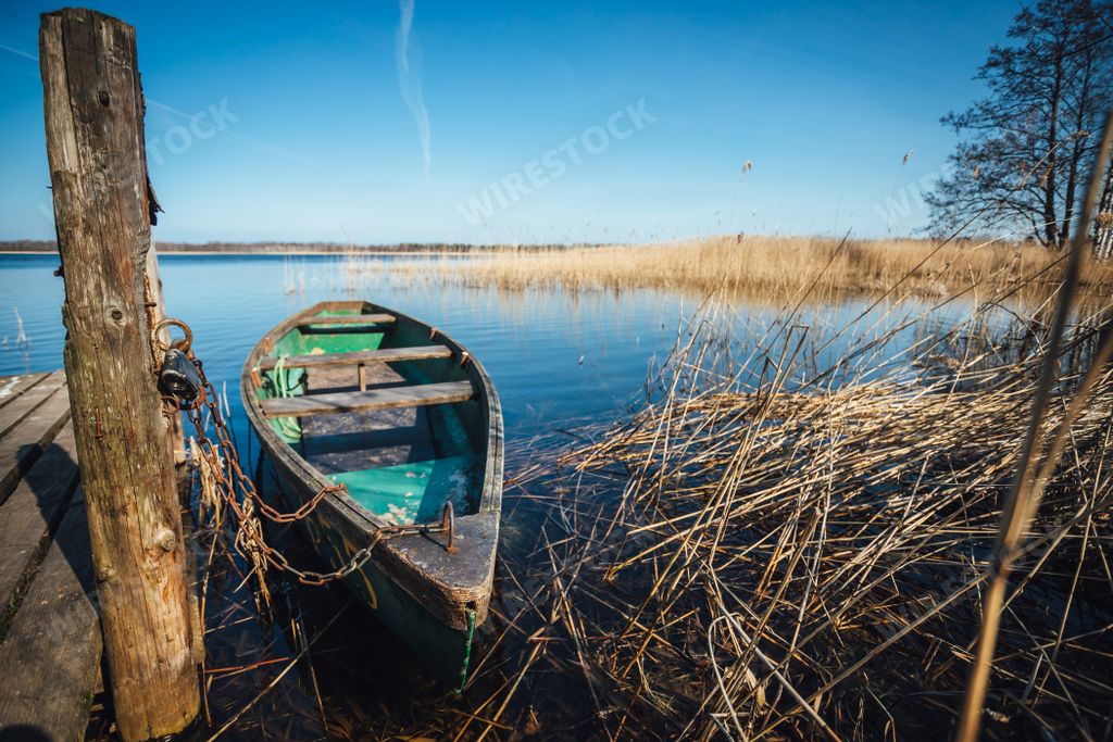A closeup shot of an old green boat floating by a wooden dock