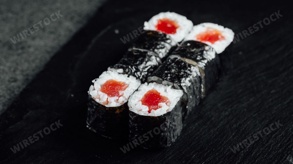 A closeup of a set of fresh delicious Tekka Maki rolls on a black plate