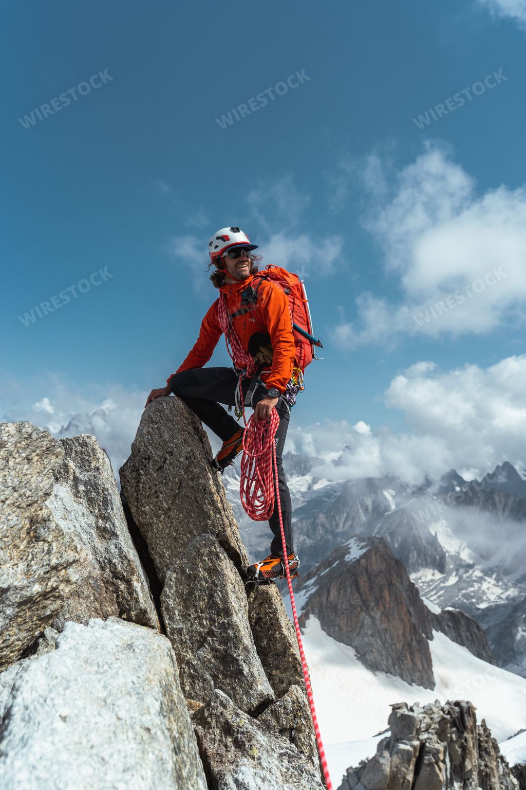 A closeup vertical shot of a person standing on a snow-covered mountain peak with a climbing rope